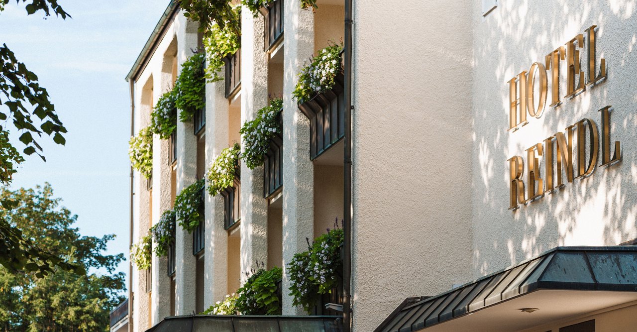 Das Hotel Reindl mit blühenden Balkonpflanzen. Sonniger Tag und klarer Himmel.